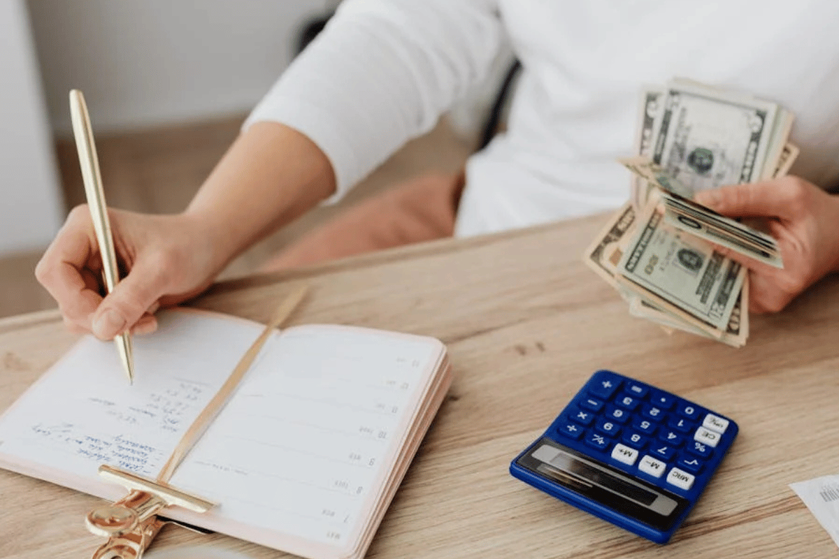 Hand holding magnifying glass over financial documents and papers on wooden desk showing nonprofit bookkeeping review.