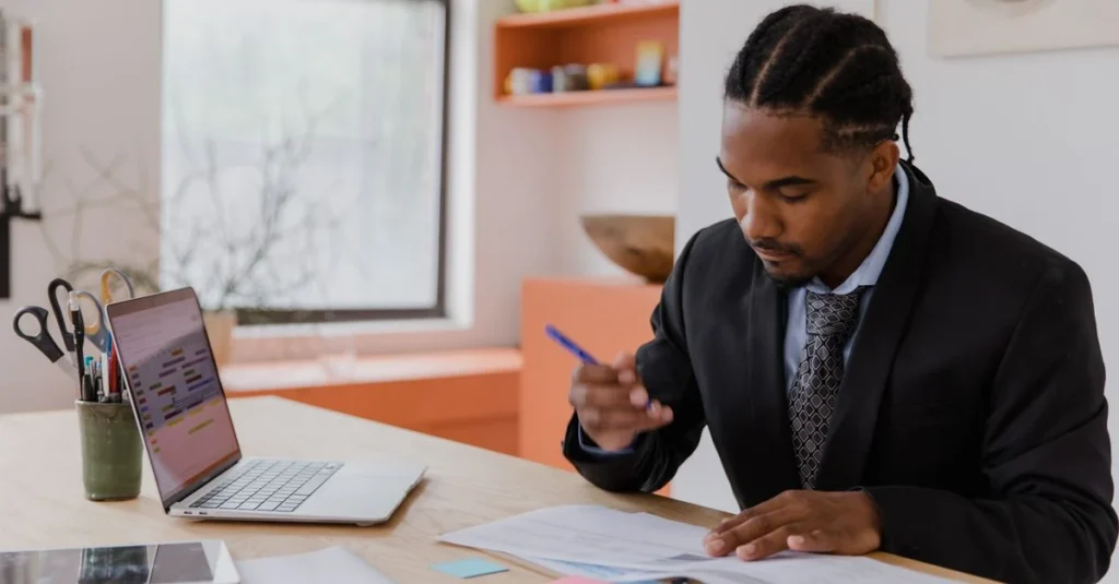 Man in business attire reviewing financial documents at desk, comparing CPA vs CFO roles and responsibilities.